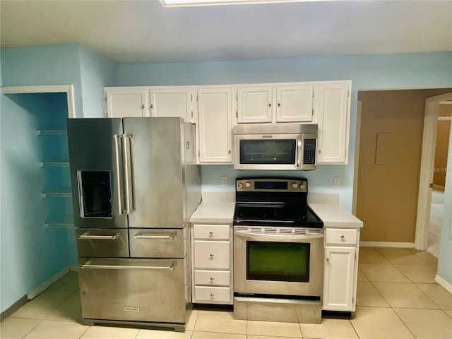 kitchen with stainless steel appliances, light tile patterned floors, and white cabinetry