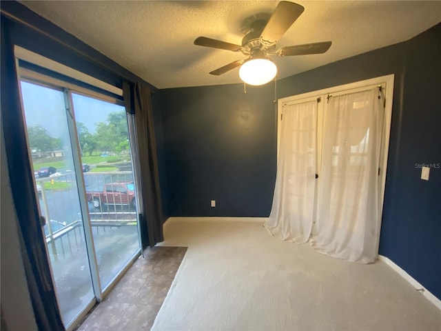 carpeted empty room with a textured ceiling and ceiling fan