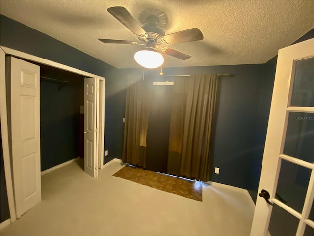 unfurnished bedroom featuring light carpet, a textured ceiling, ceiling fan, and a closet