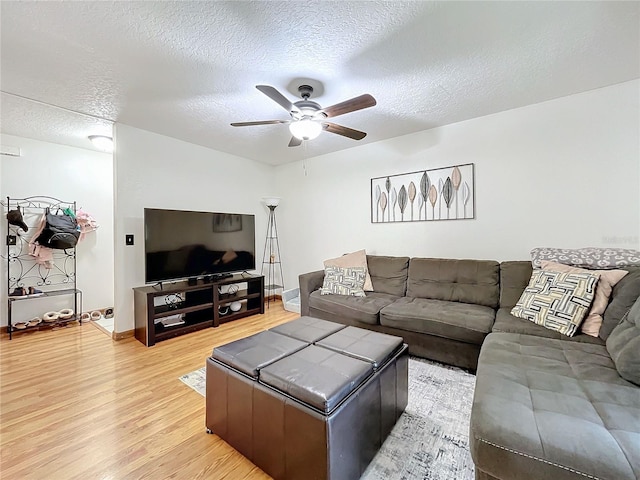 living room with a textured ceiling, ceiling fan, and light hardwood / wood-style floors