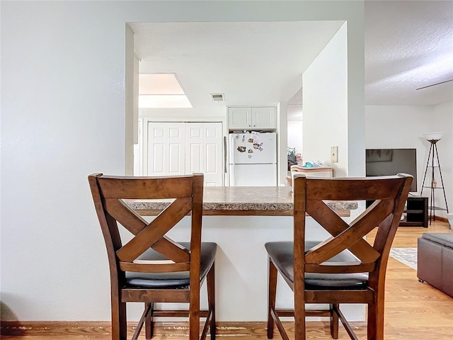 bar featuring white fridge and light hardwood / wood-style flooring