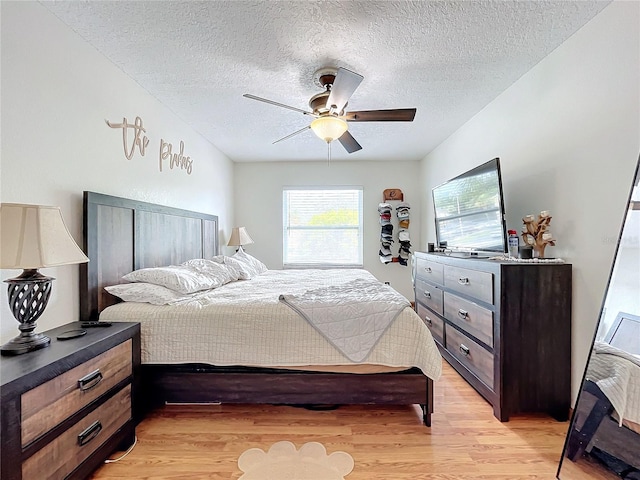 bedroom with light wood-type flooring, a textured ceiling, and ceiling fan