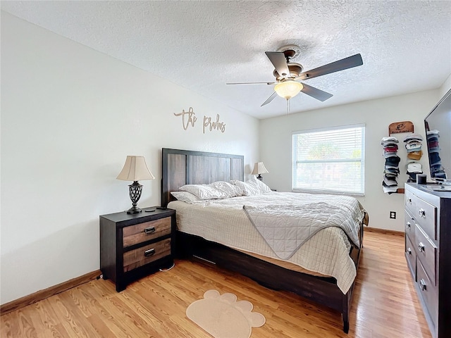 bedroom with a textured ceiling, ceiling fan, and light wood-type flooring