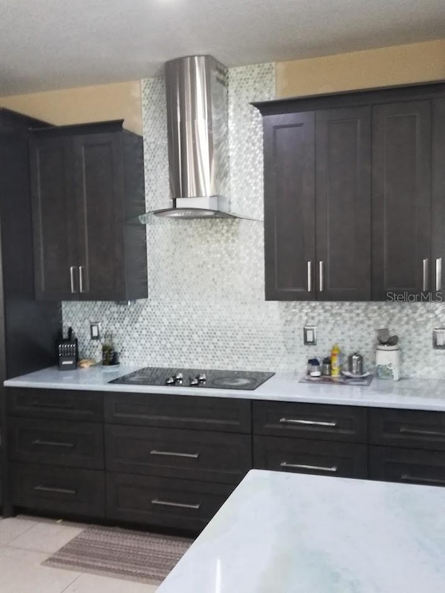 kitchen with black electric stovetop, light tile patterned flooring, wall chimney range hood, and tasteful backsplash