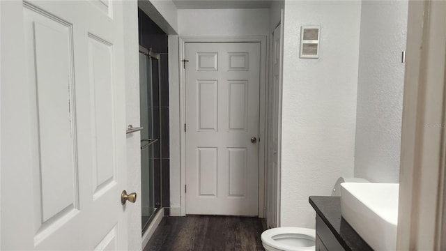 bathroom with vanity, toilet, hardwood / wood-style flooring, and a shower with shower door