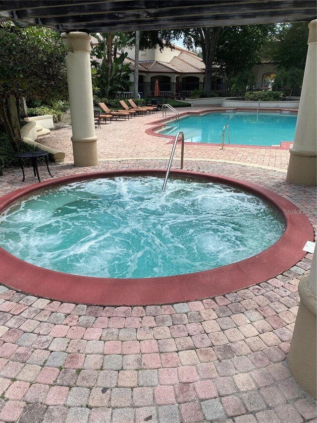 view of swimming pool with a hot tub and a patio