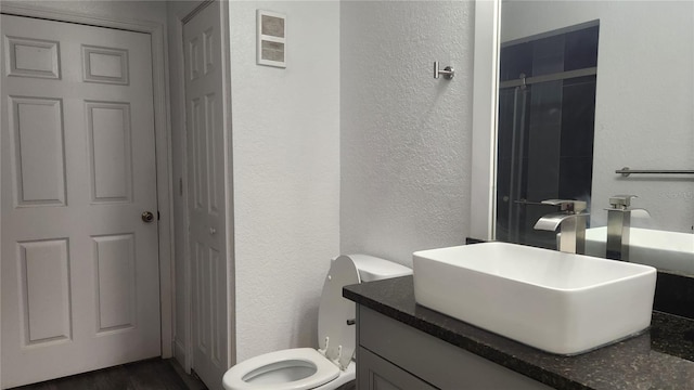 bathroom featuring a shower with door, vanity, toilet, and hardwood / wood-style flooring