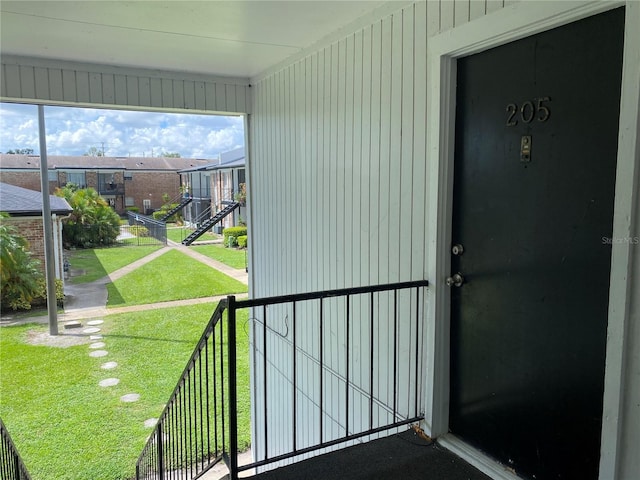 doorway to property with a balcony and a lawn