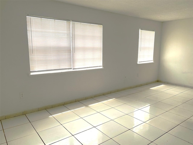 spare room with a textured ceiling and light tile patterned floors