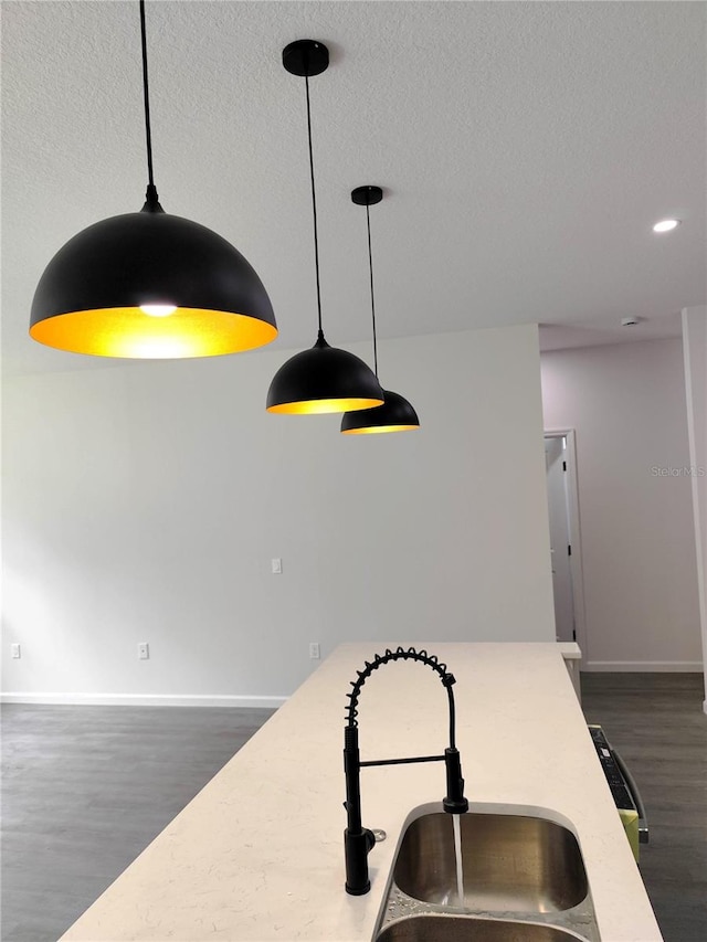 interior details with a textured ceiling, sink, dark hardwood / wood-style floors, and decorative light fixtures