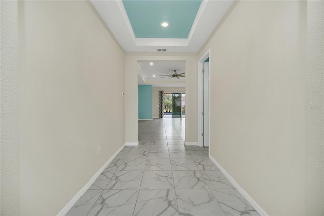 corridor featuring a raised ceiling