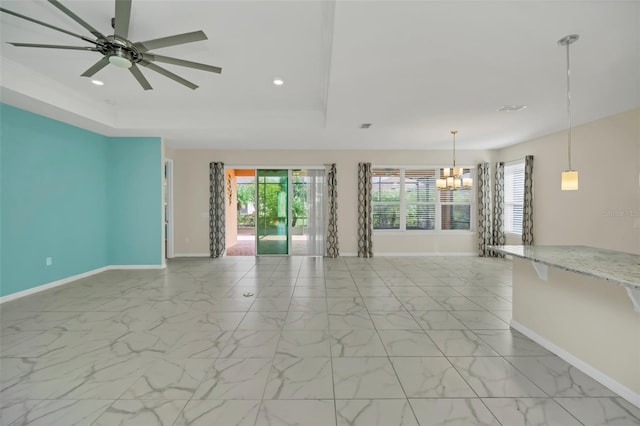 unfurnished living room featuring ceiling fan with notable chandelier