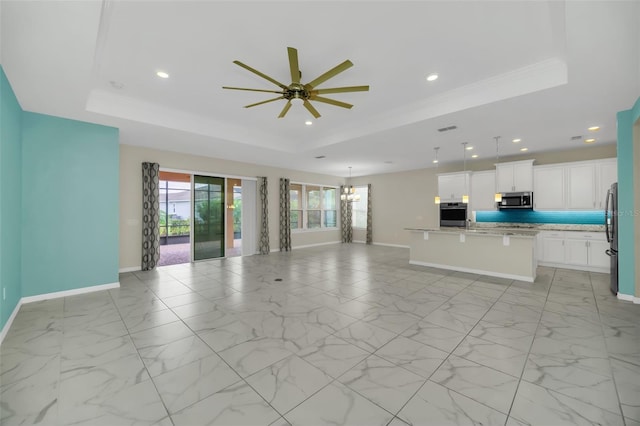 unfurnished living room featuring ceiling fan with notable chandelier, a raised ceiling, and crown molding