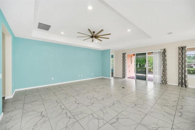 spare room featuring a tray ceiling and ceiling fan