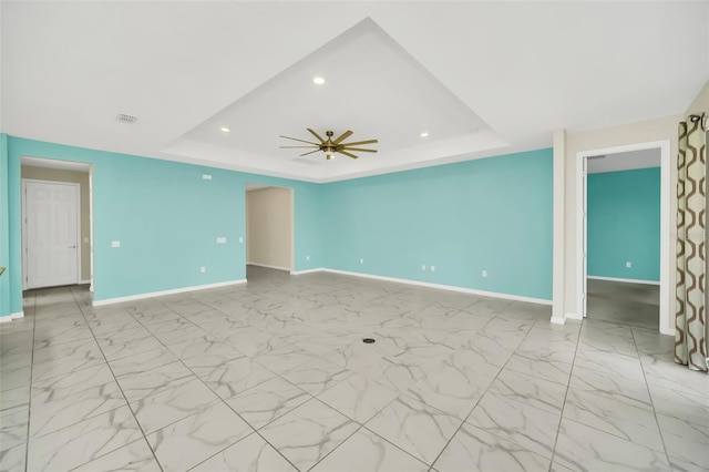 spare room featuring a raised ceiling and ceiling fan