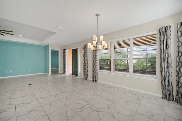 empty room featuring ceiling fan with notable chandelier and a tray ceiling