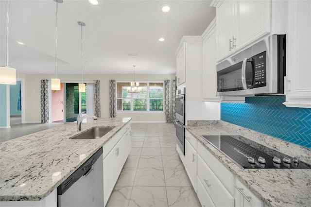 kitchen featuring pendant lighting, stainless steel appliances, an island with sink, sink, and white cabinets