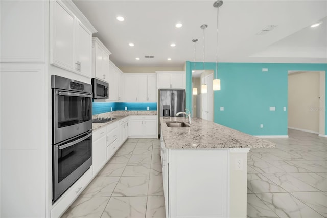 kitchen featuring appliances with stainless steel finishes, a center island with sink, and white cabinetry