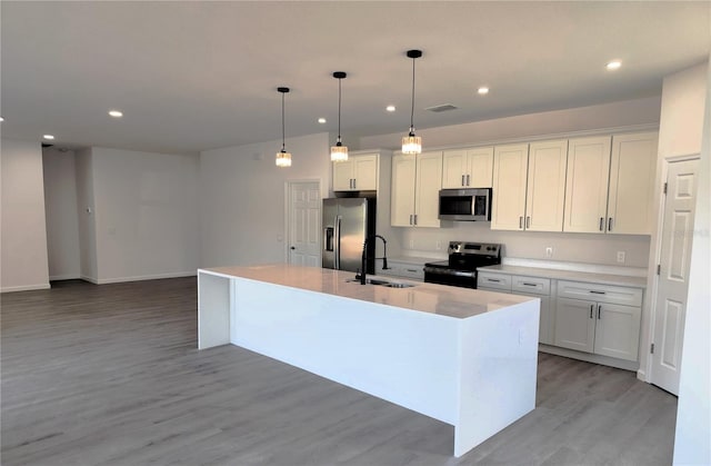 kitchen featuring white cabinets, sink, light hardwood / wood-style flooring, an island with sink, and stainless steel appliances