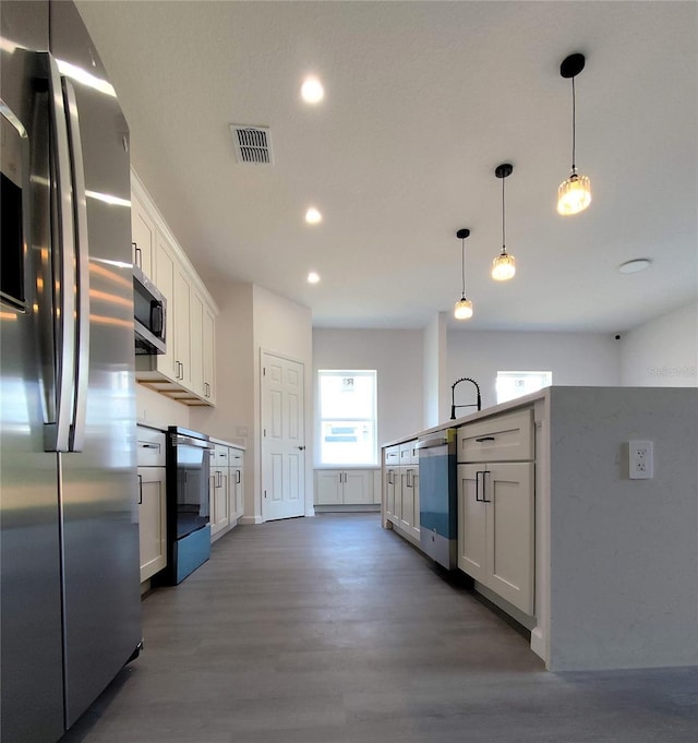 kitchen with white cabinets, decorative light fixtures, and appliances with stainless steel finishes