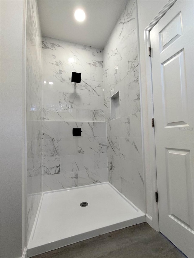 bathroom with hardwood / wood-style floors and tiled shower