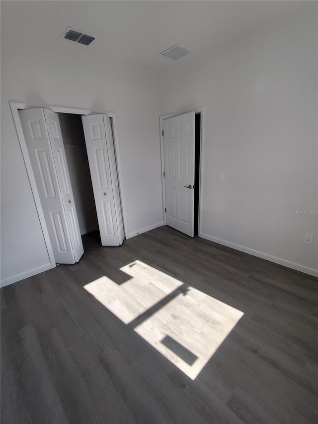 unfurnished bedroom with a closet and dark hardwood / wood-style floors