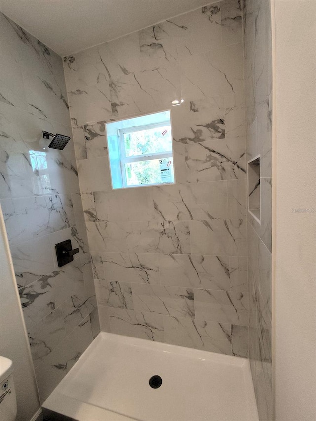 bathroom with toilet and tiled shower