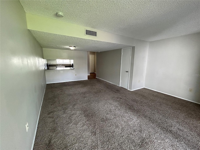 spare room featuring a textured ceiling and dark carpet