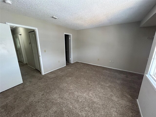 unfurnished bedroom featuring dark carpet and a textured ceiling