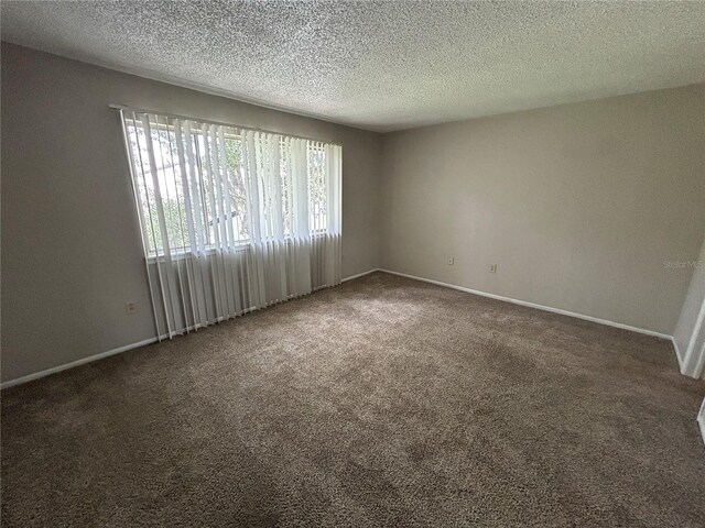 spare room with dark carpet and a textured ceiling