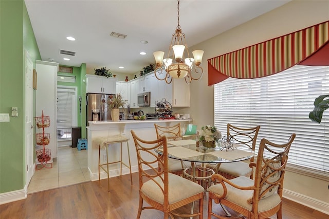 dining space with light hardwood / wood-style flooring and a notable chandelier