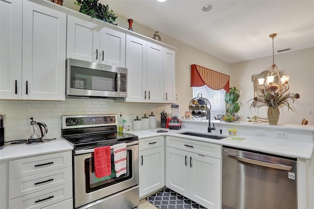 kitchen featuring backsplash, stainless steel appliances, sink, a chandelier, and white cabinets