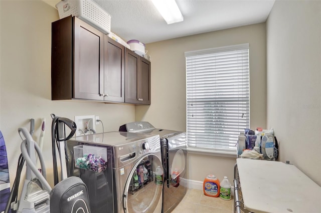 laundry room featuring light tile patterned flooring, washing machine and clothes dryer, cabinets, and a healthy amount of sunlight