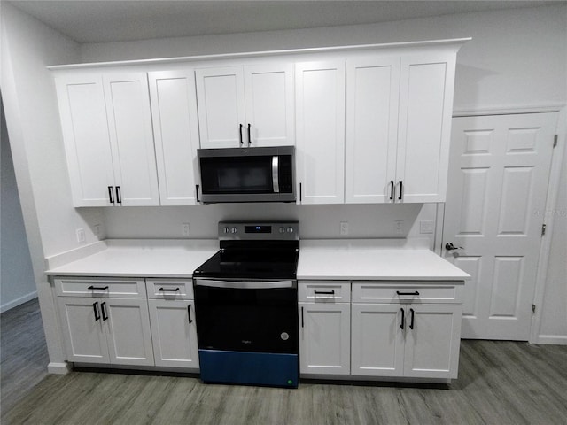 kitchen with appliances with stainless steel finishes, white cabinetry, and light hardwood / wood-style floors