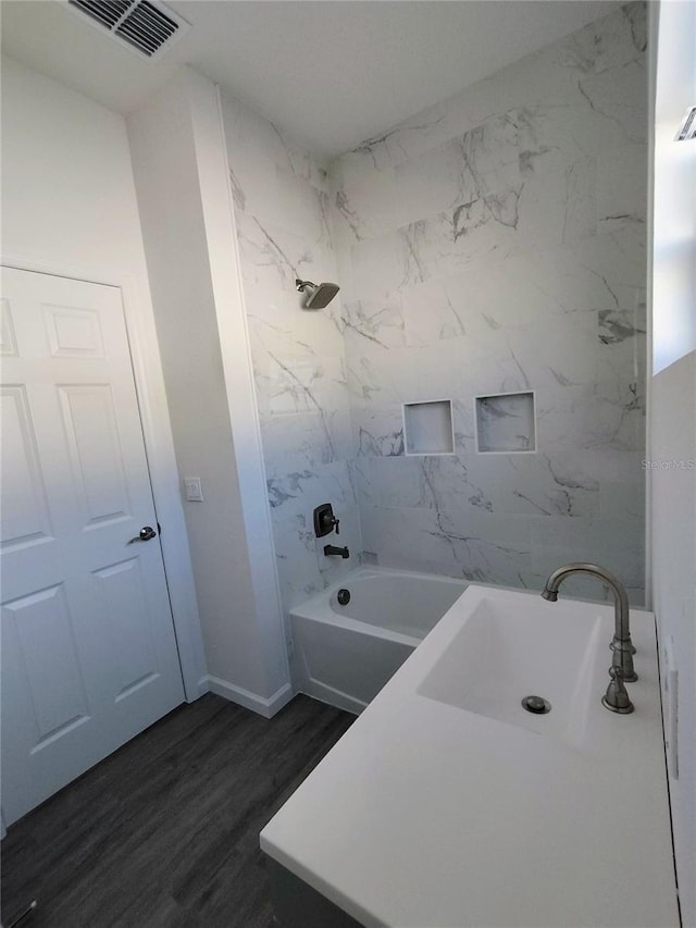 bathroom featuring tiled shower / bath, hardwood / wood-style flooring, and sink