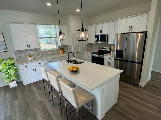 kitchen with appliances with stainless steel finishes, a breakfast bar, sink, pendant lighting, and an island with sink