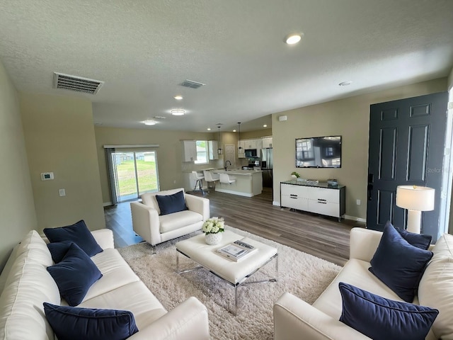 living room with hardwood / wood-style flooring, sink, and a textured ceiling