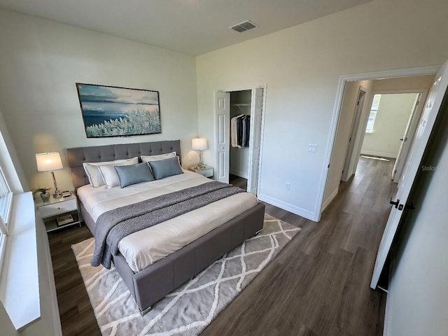 bedroom with a walk in closet, dark hardwood / wood-style floors, and a closet