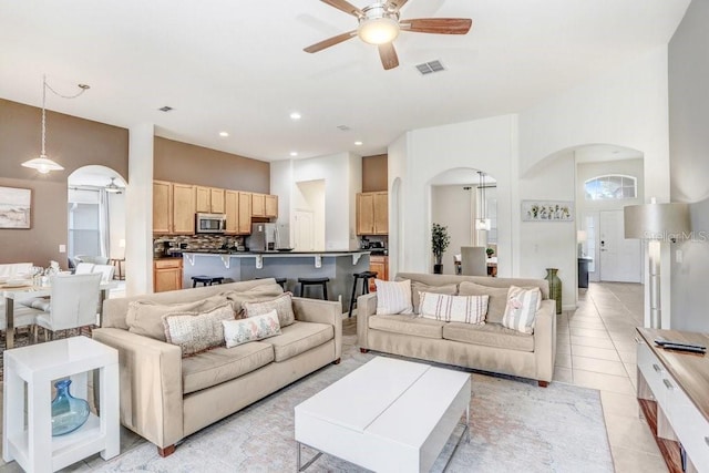 living room featuring ceiling fan, a towering ceiling, and light tile patterned floors