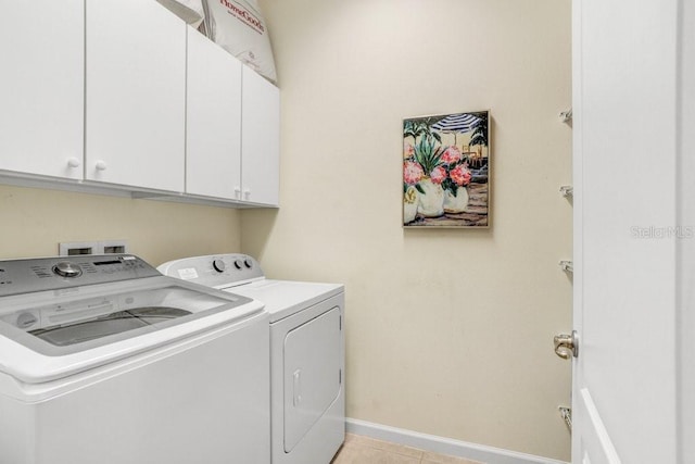 clothes washing area featuring washing machine and clothes dryer, cabinets, and light tile patterned floors