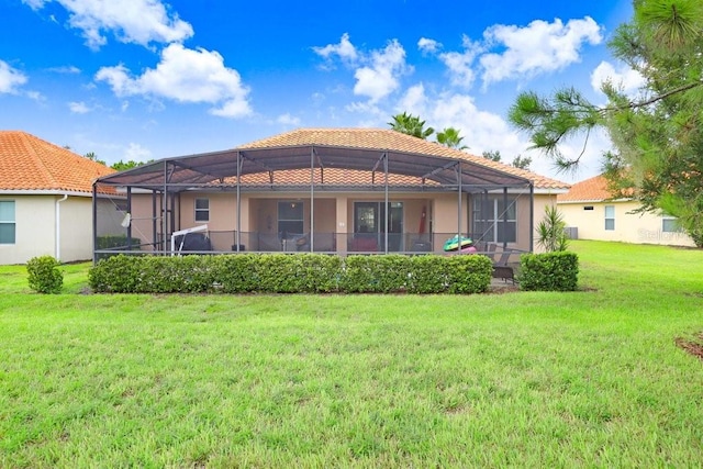 back of property with a yard and glass enclosure