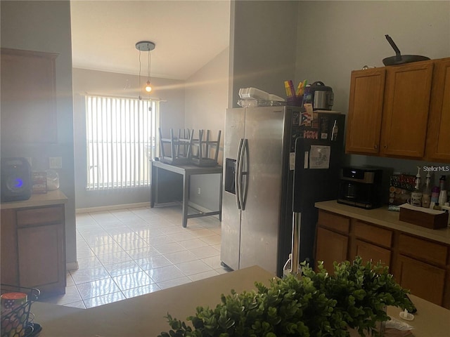 kitchen featuring stainless steel fridge with ice dispenser, vaulted ceiling, light tile patterned floors, and pendant lighting