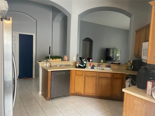 kitchen with stainless steel refrigerator, sink, black dishwasher, kitchen peninsula, and light tile patterned floors