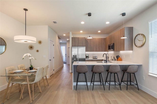 kitchen with appliances with stainless steel finishes, plenty of natural light, kitchen peninsula, and a breakfast bar