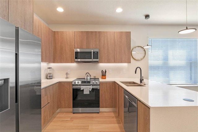 kitchen with light hardwood / wood-style flooring, stainless steel appliances, sink, and decorative light fixtures