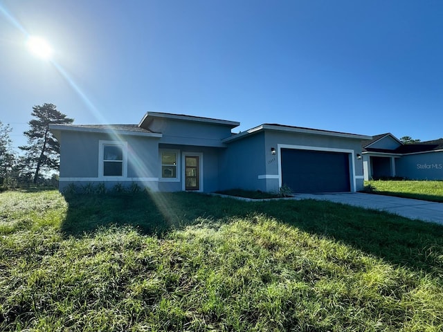 view of front facade with a garage, a front yard, driveway, and stucco siding