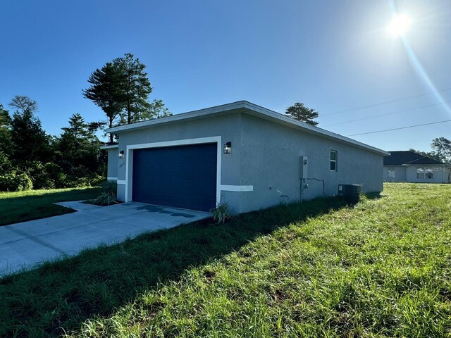 garage featuring a lawn and central AC unit