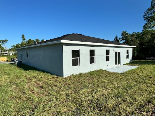 rear view of house featuring a lawn, a patio, and stucco siding