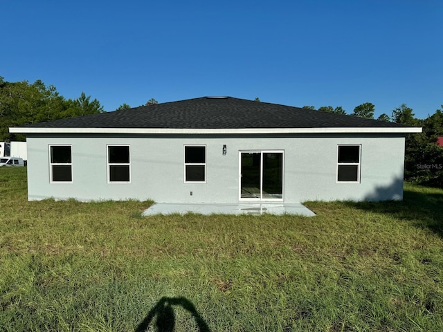 back of property with a yard and stucco siding