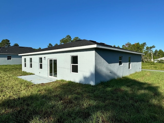 rear view of property with a patio area, a lawn, and stucco siding